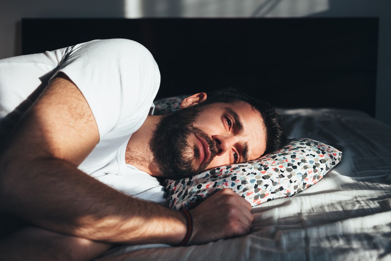 man laying in bed feeling sick due to using poppers